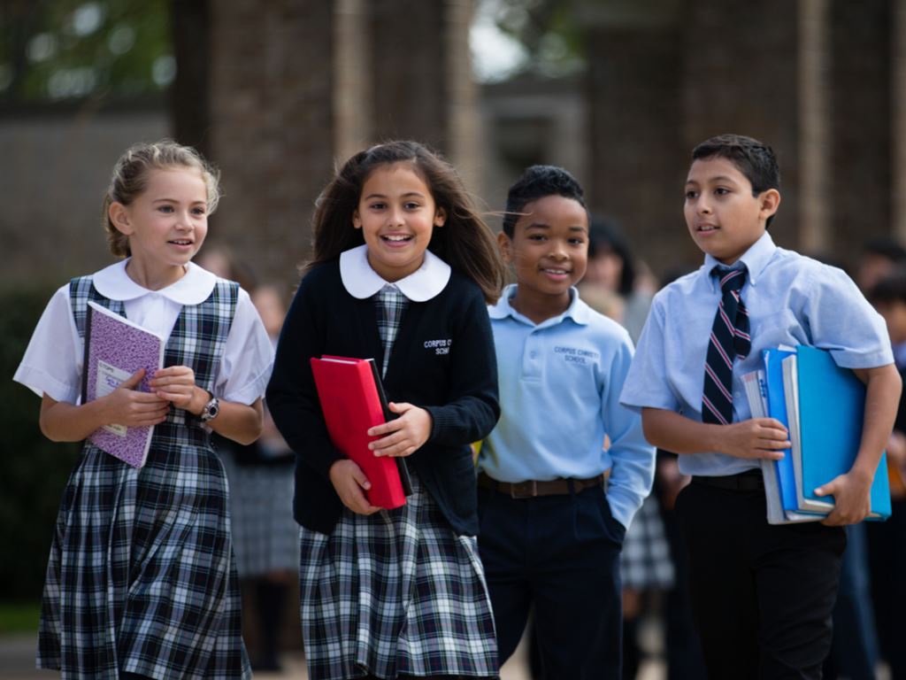 Catholic school children happily walking on school campus.